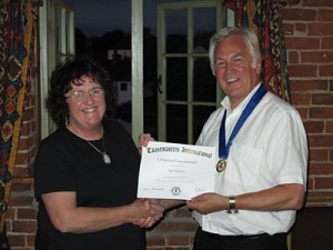 Sue Hutton receives her Competent Communicator award certificate from President John Cox